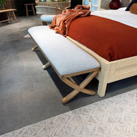 Close-up of bench next to red blanket on bed.