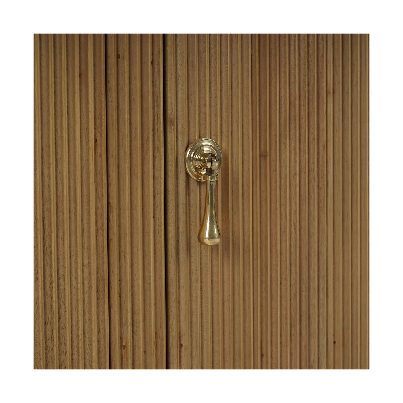 Close-up of sideboard handle on reeded wood surface.