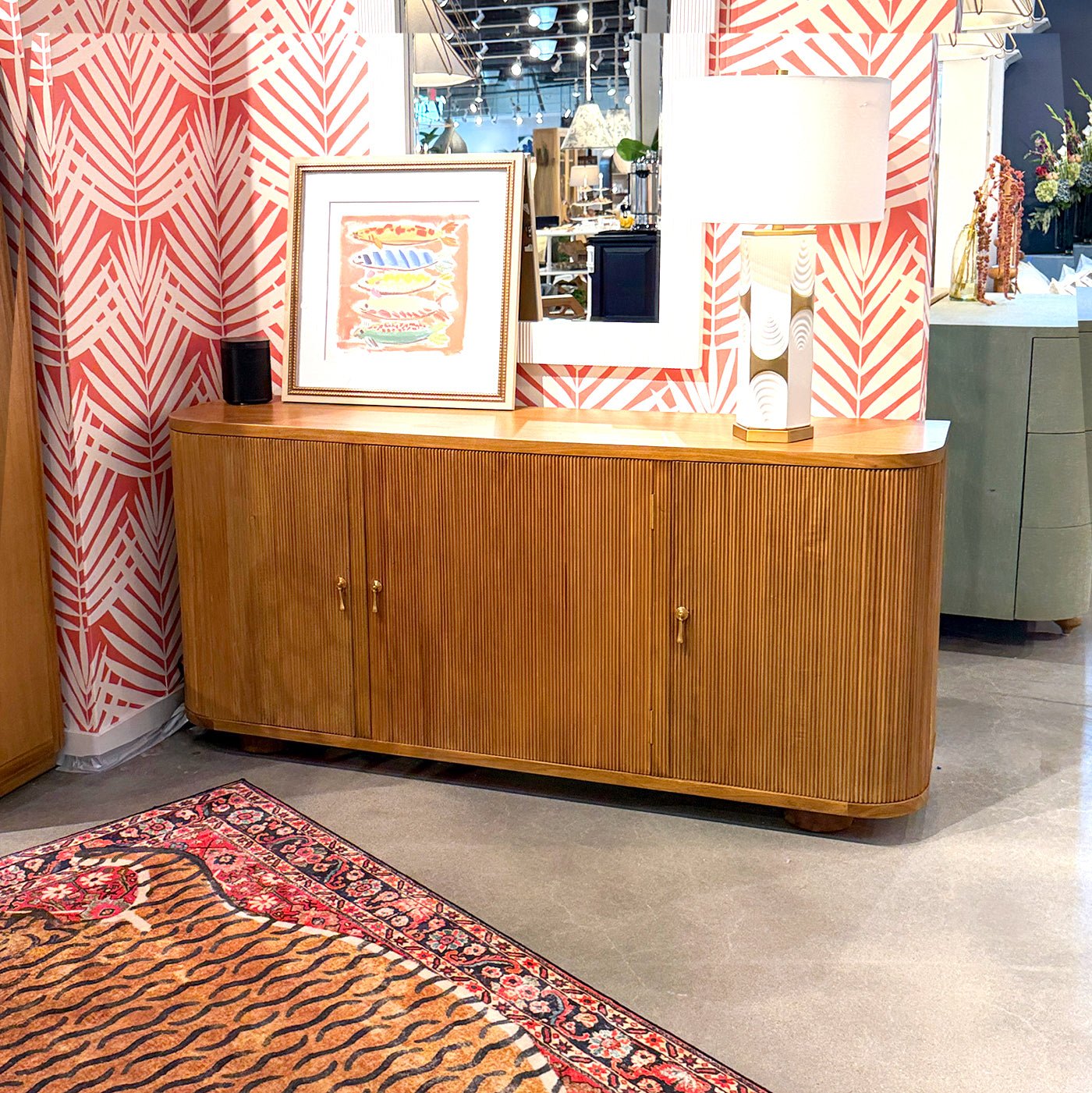 Sideboard displayed in showroom with colorful wallpaper.
