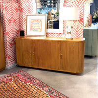 Sideboard displayed in showroom with colorful wallpaper.