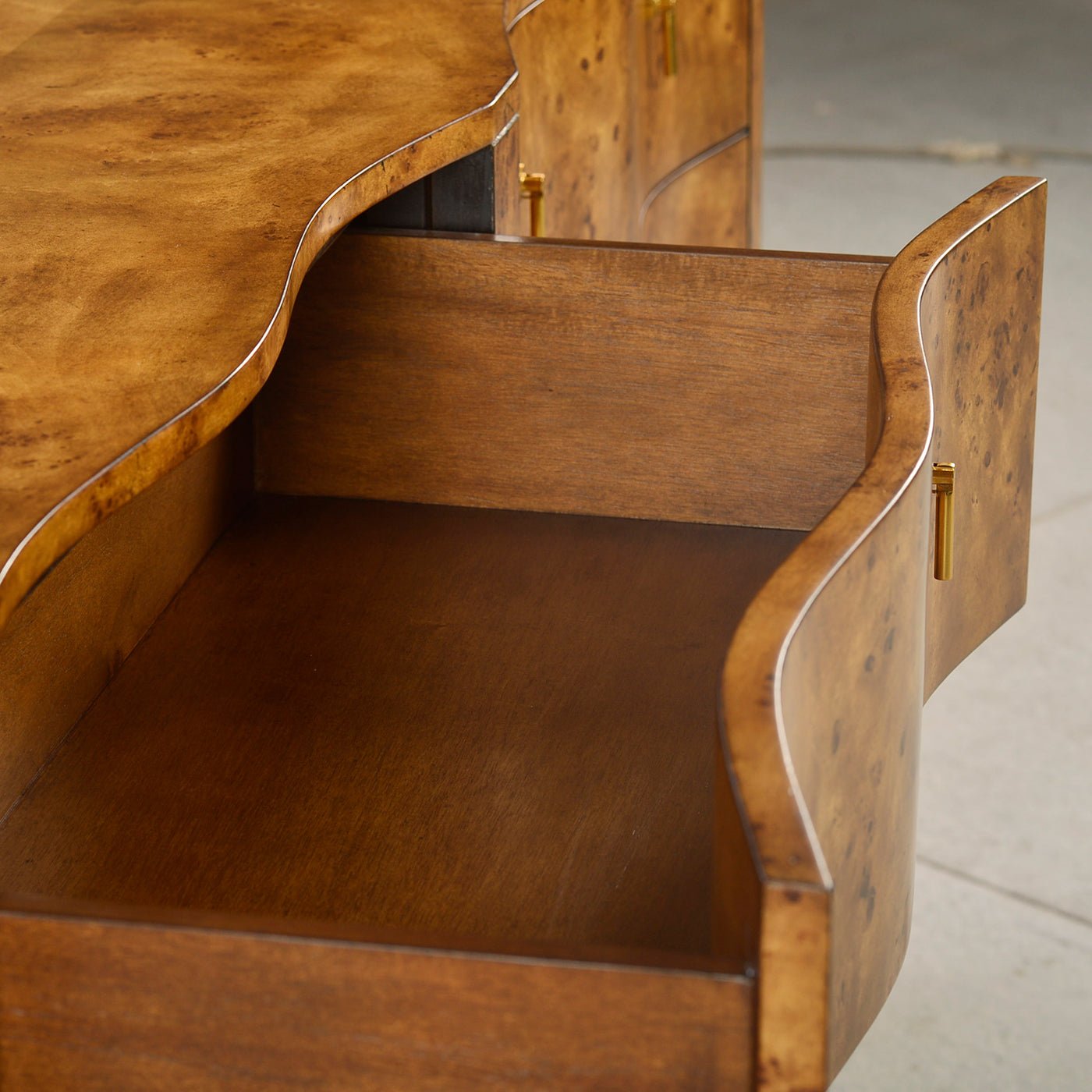 Inner view of drawer in serpentine burl wood dresser.