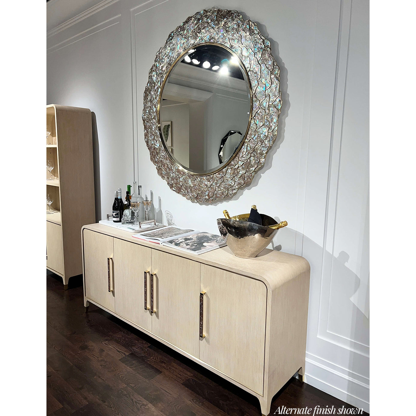 Sideboard buffet styled in room with round mirror above.