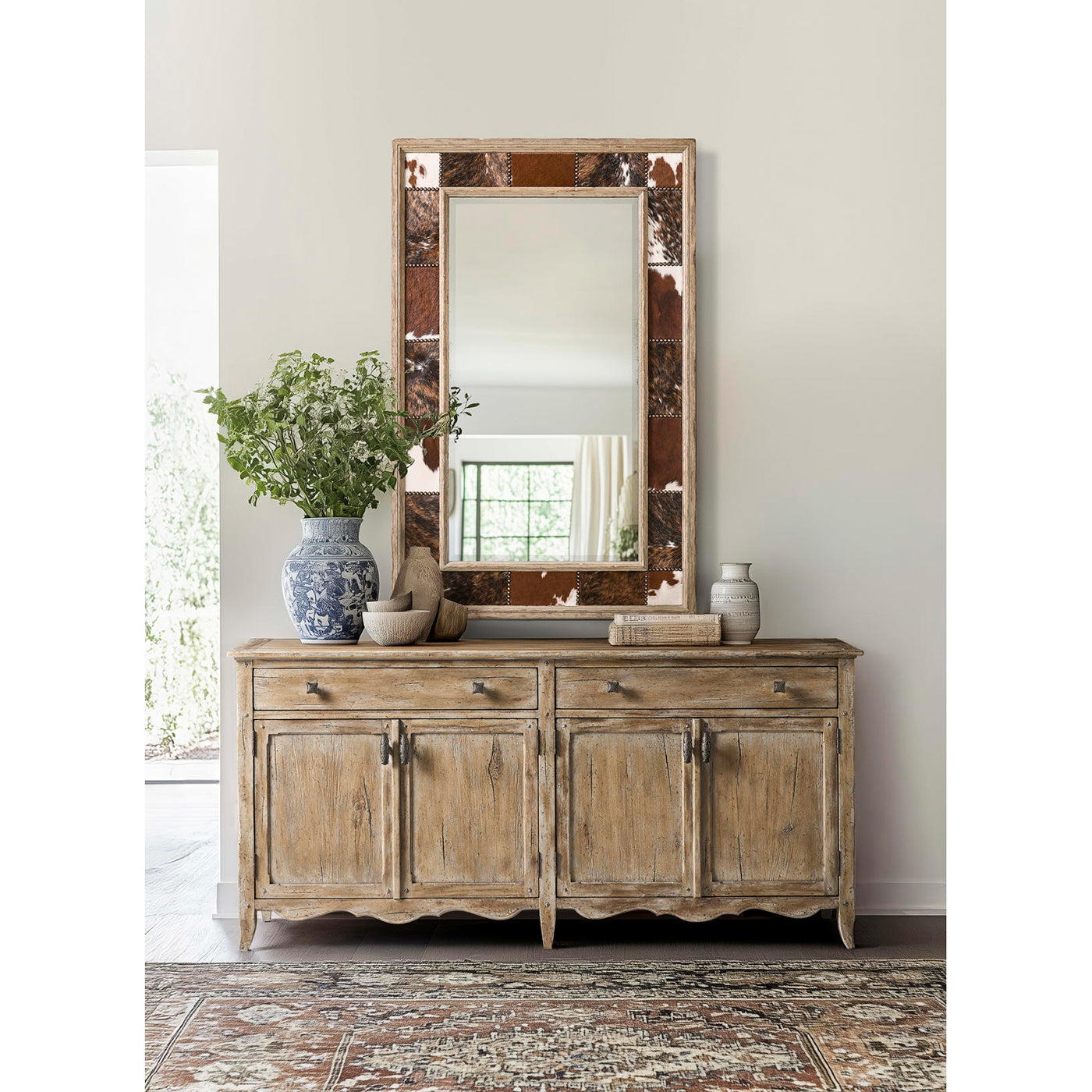 Sideboard in room with mirror and decorations.