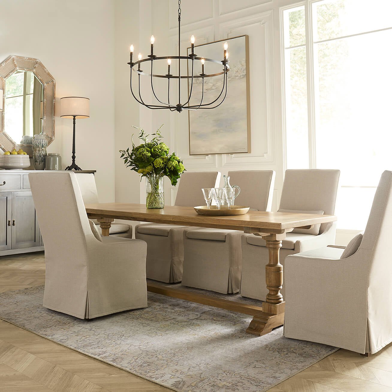 Bright dining room with slipcovered chairs and chandelier.