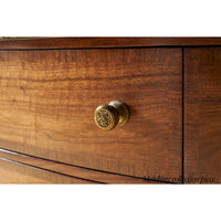 Detailed brass knob on wooden nightstand drawer, close-up.