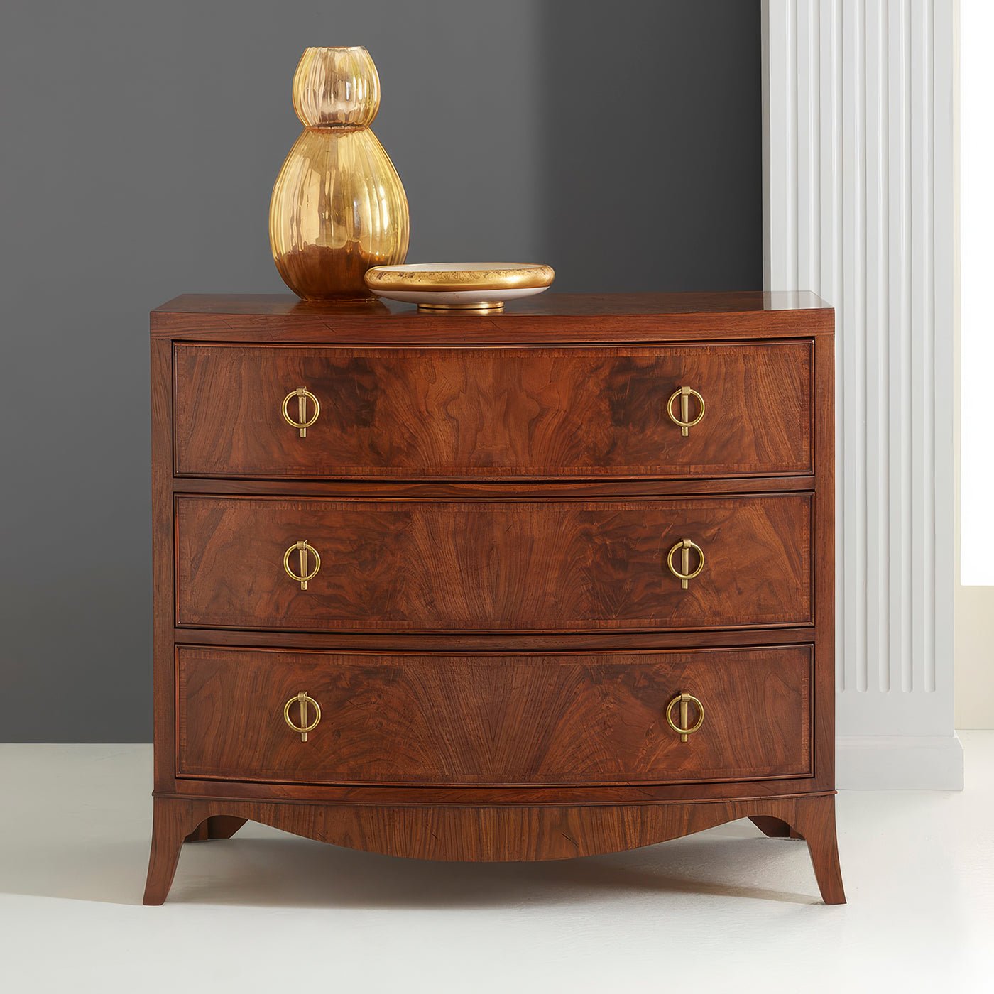 Styled walnut chest of drawers with decorative items on top.