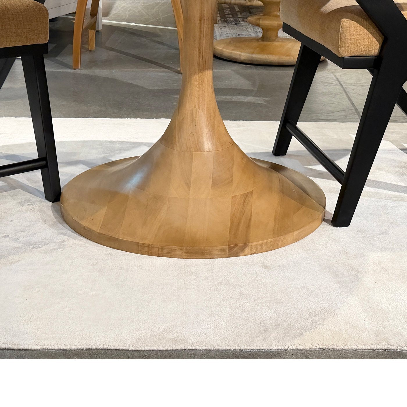Pedestal base of wooden tulip dining table with chairs.