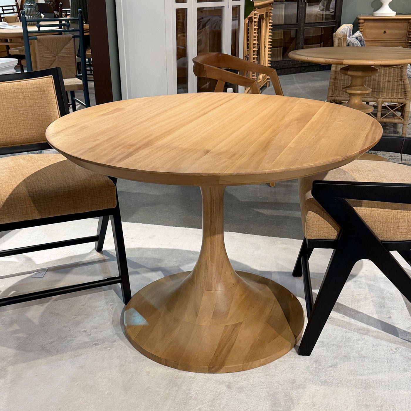Round wooden tulip dining table with chairs, in room.