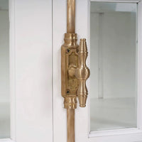 Detailed view of white credenza's brass door handle.