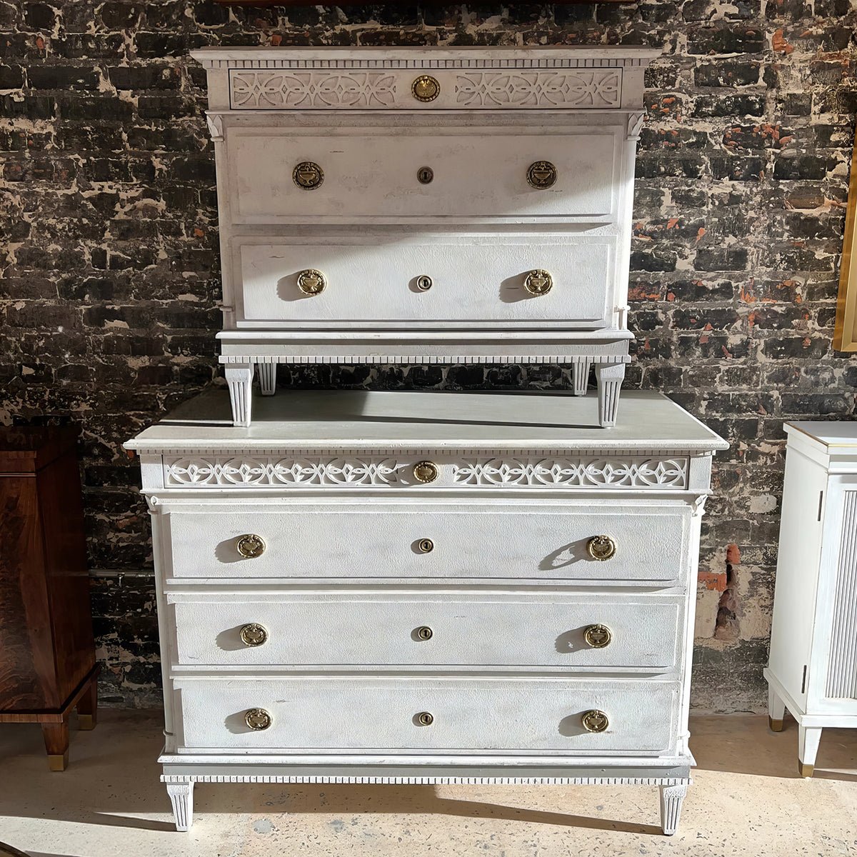 Two Gustavian style bedside chests, exposed brick background.