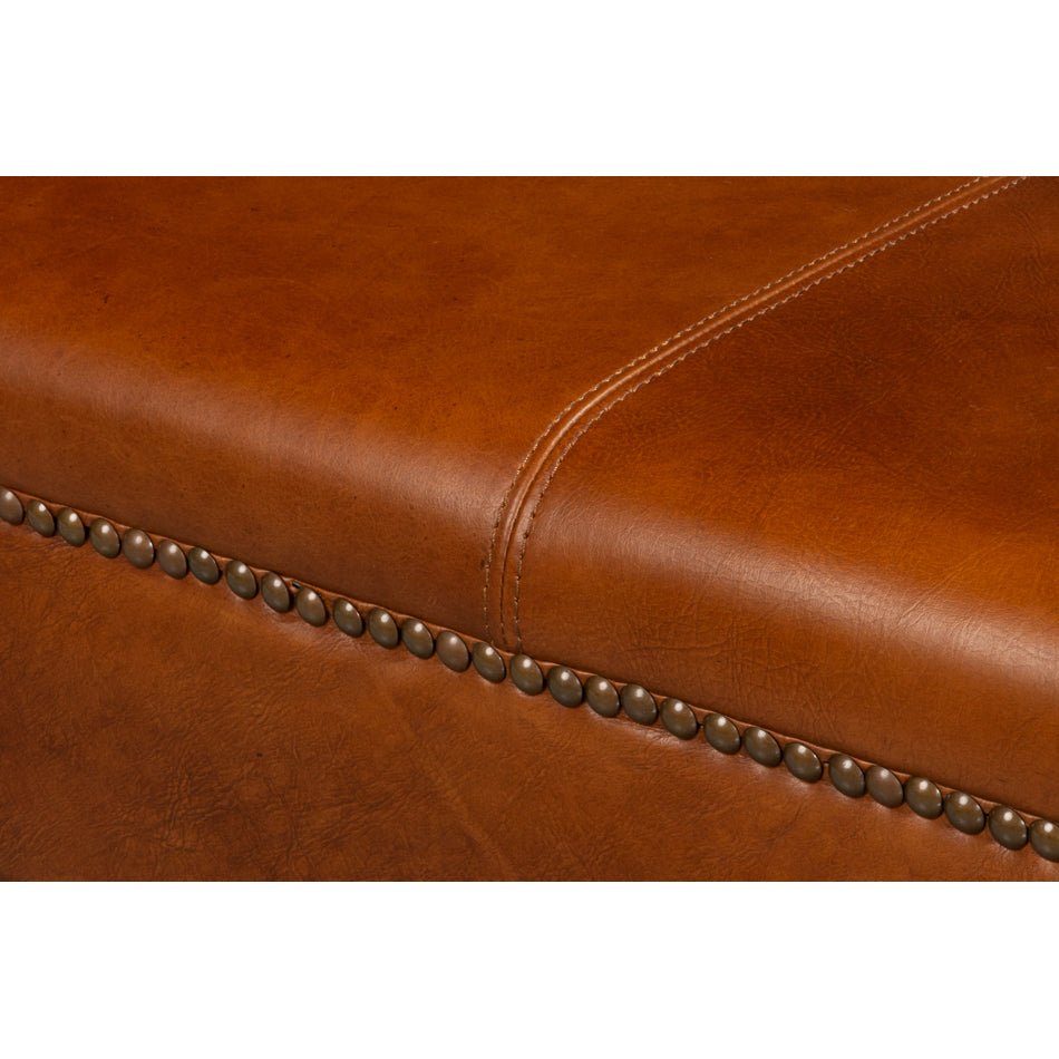 Close-up stitching detail on brown leather ottoman.