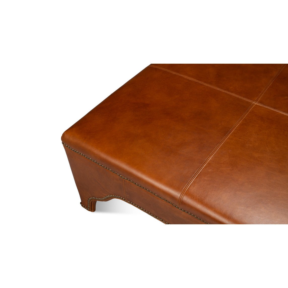 Close-up corner view of brown leather ottoman.