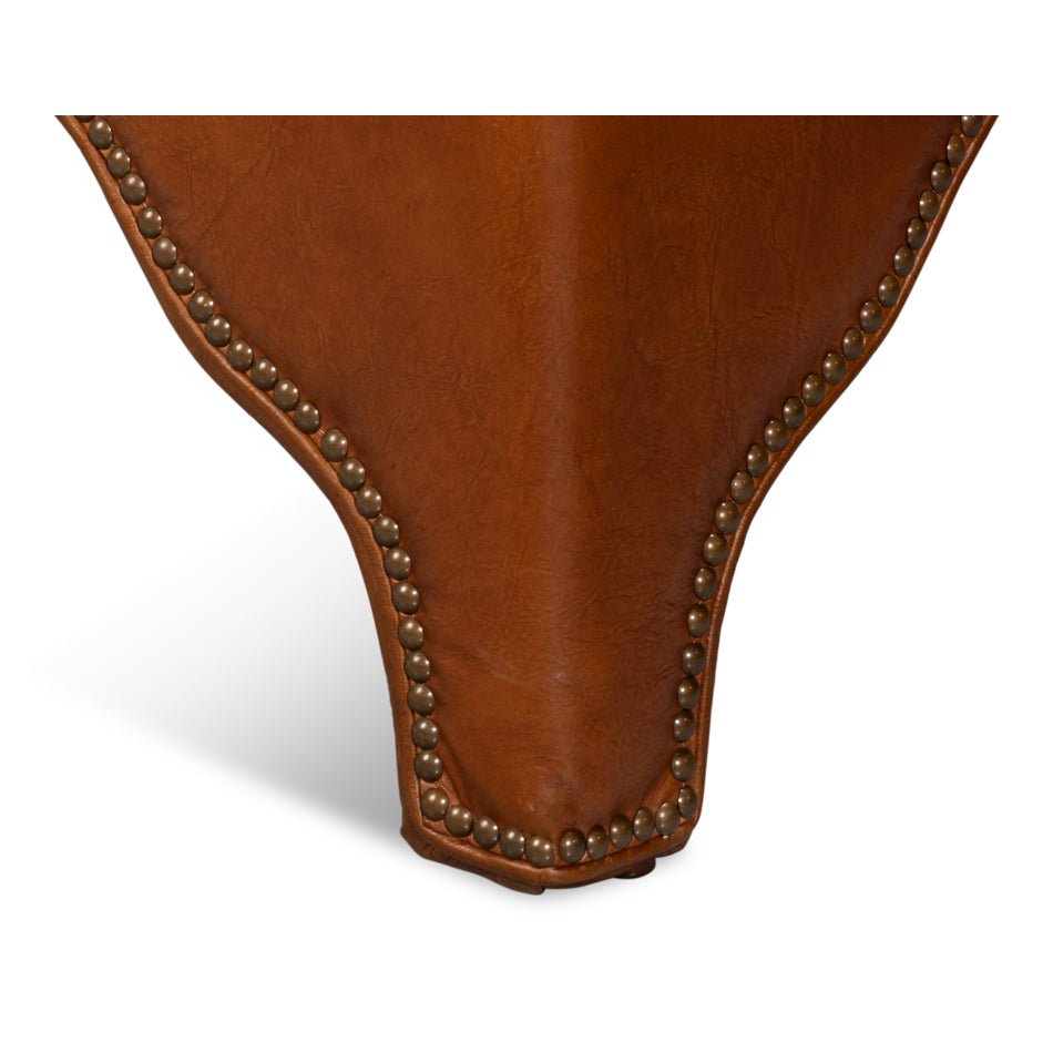 Leg detail of brown leather ottoman with trim.