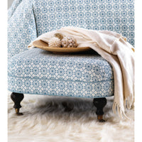 Blue-patterned ottoman with tray and beige blanket.