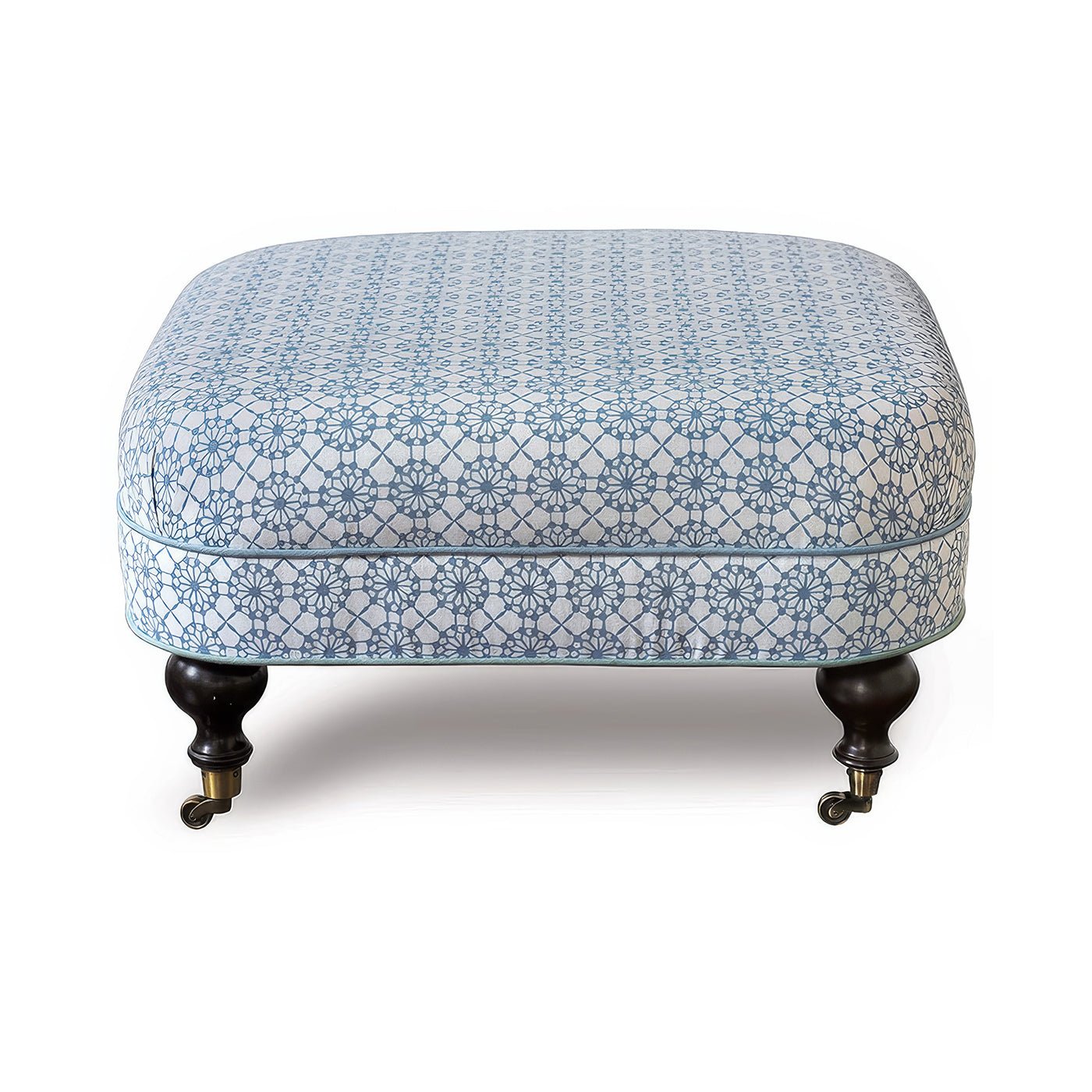 Blue-patterned ottoman with dark wooden legs on wheels.