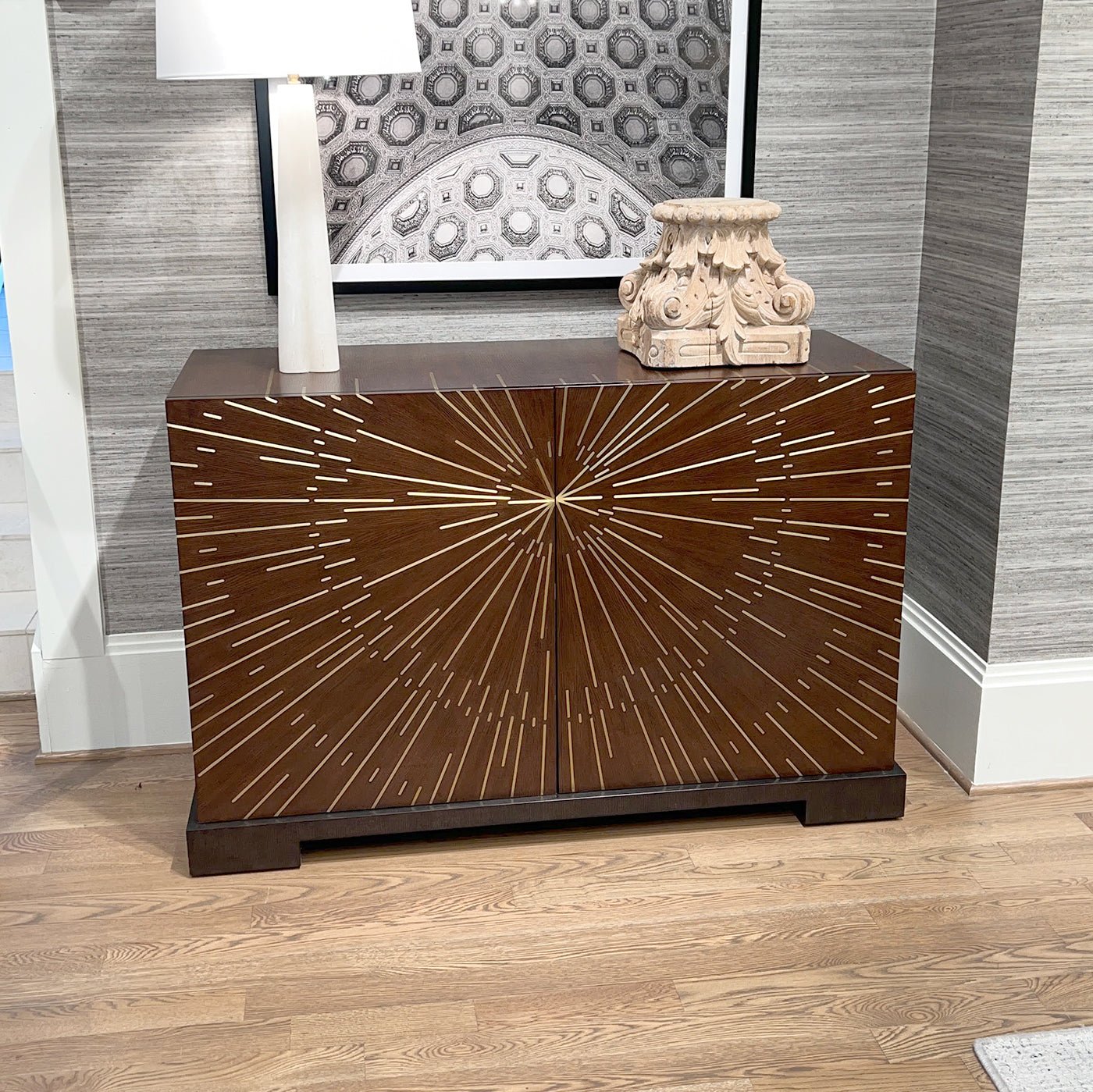 Starburst art deco cabinet with decor and lamp.