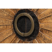 Close-up of circular handle on sunburst wood cabinet.