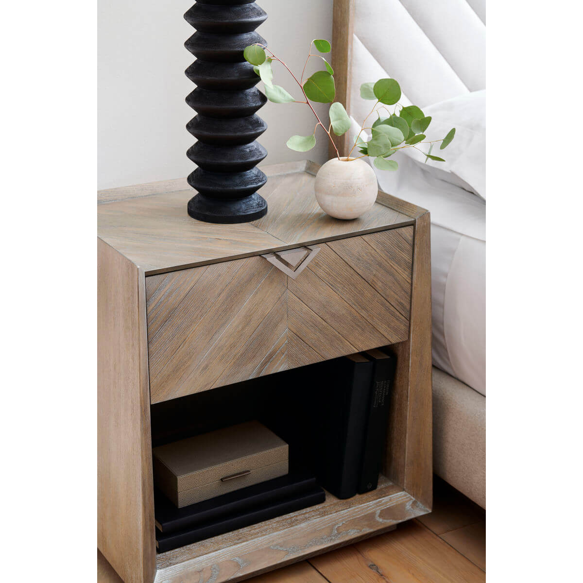 Decorated tapered ash nightstand close-up with books and vase.