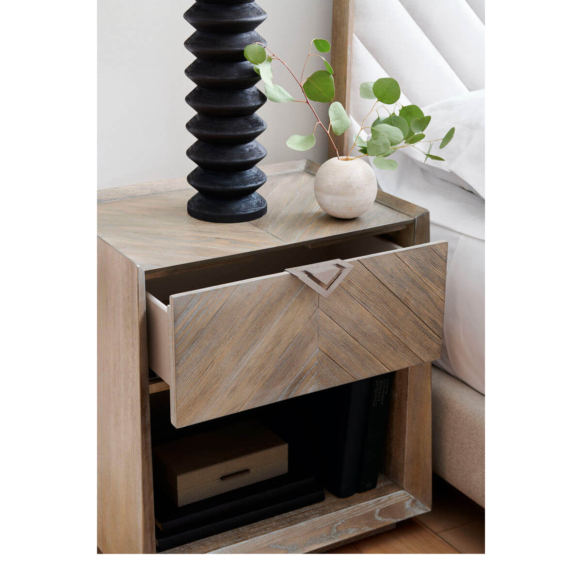 Tapered ash nightstand with open drawer and decor.