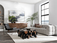 Gray chaise sectional styled in a modern living room with a dark sculptural coffee table
