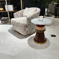 Eclectic accent table beside patterned armchair.