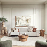 Gray three-piece sofa styled with pillows, a throw and a round wood coffee table in a living room
