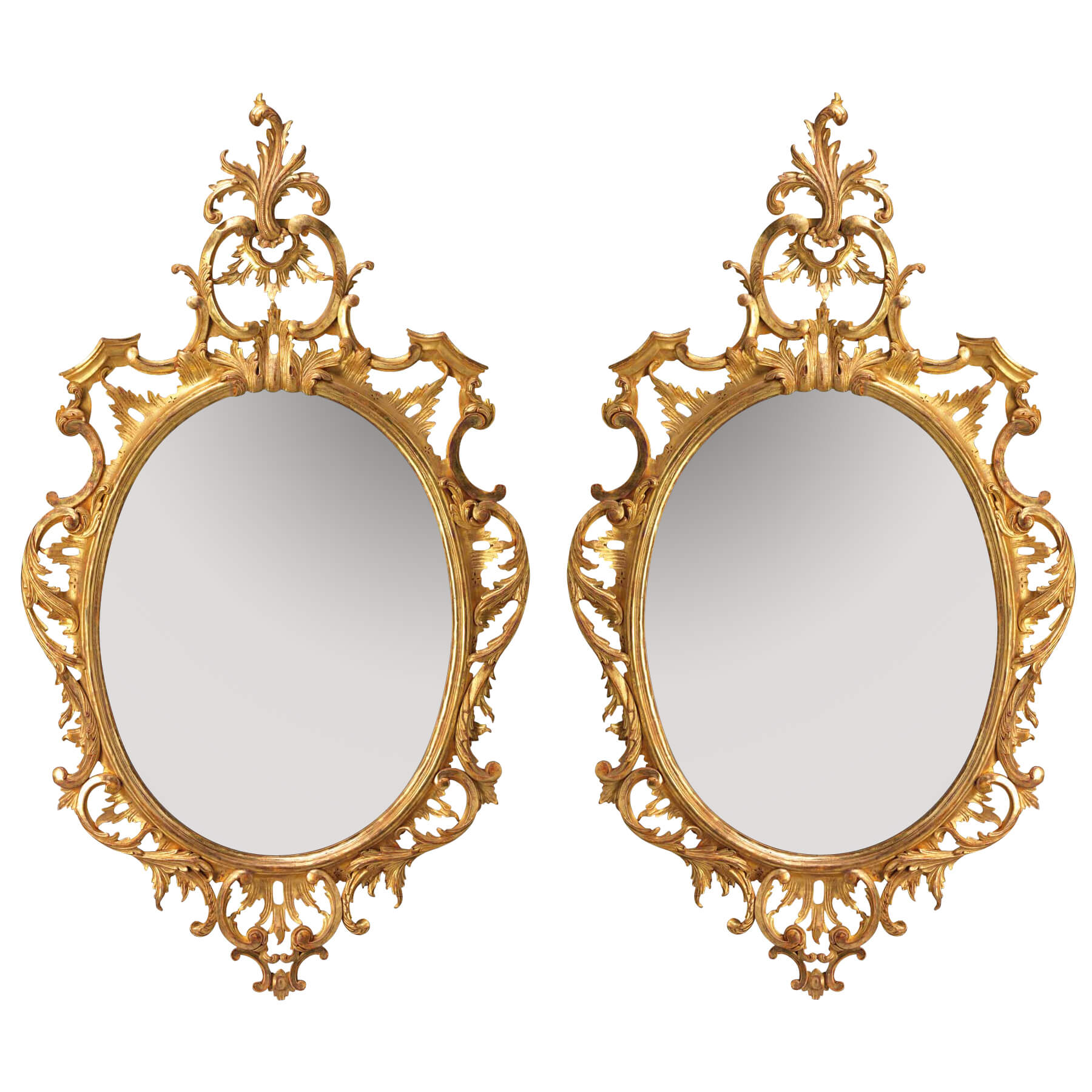 Pair of traditional Chippendale oval mirrors with intricate gold frames.