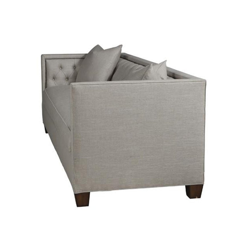 Beige tufted sofa, side view with decorative pillows.