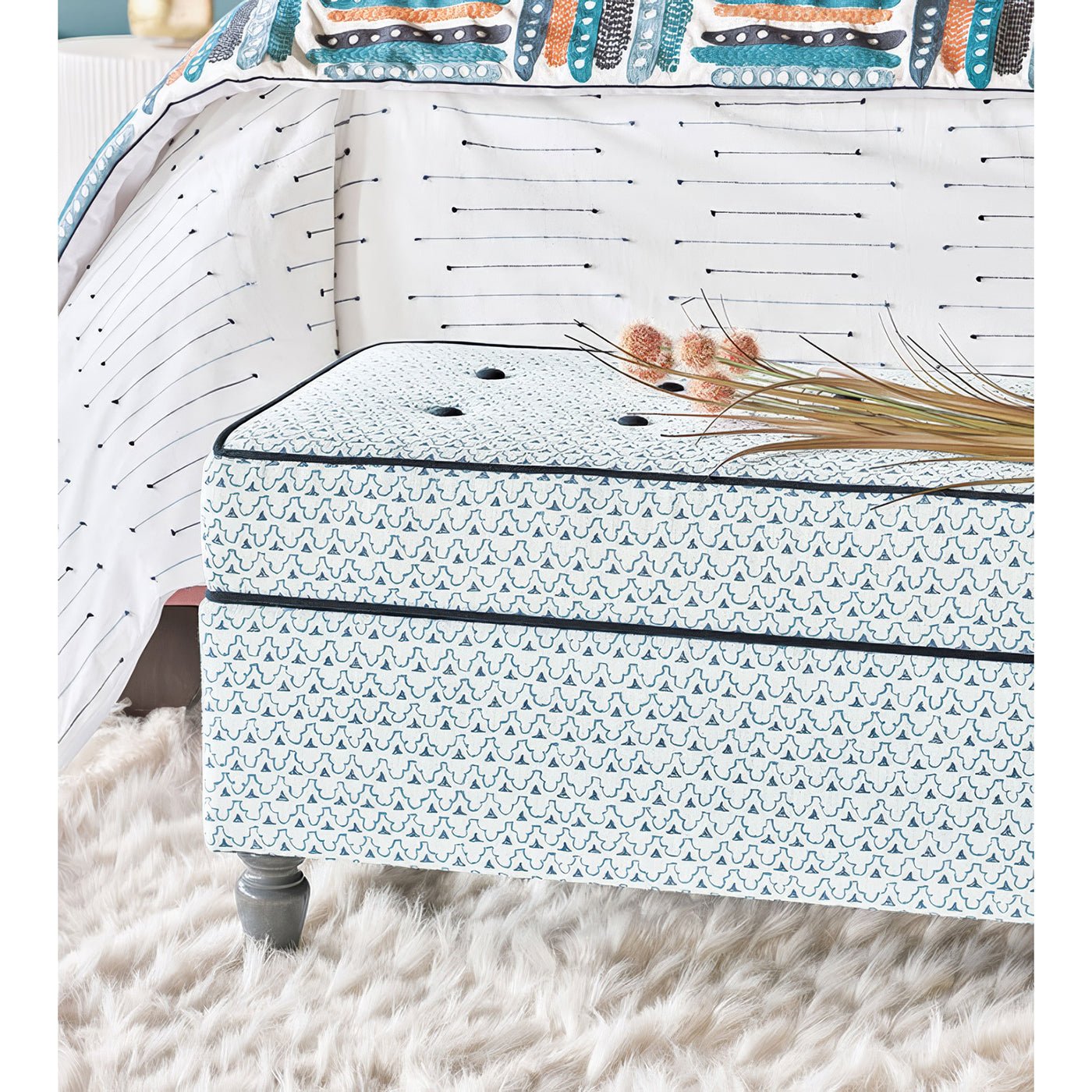 Trellis print ottoman styled in bedroom setting.