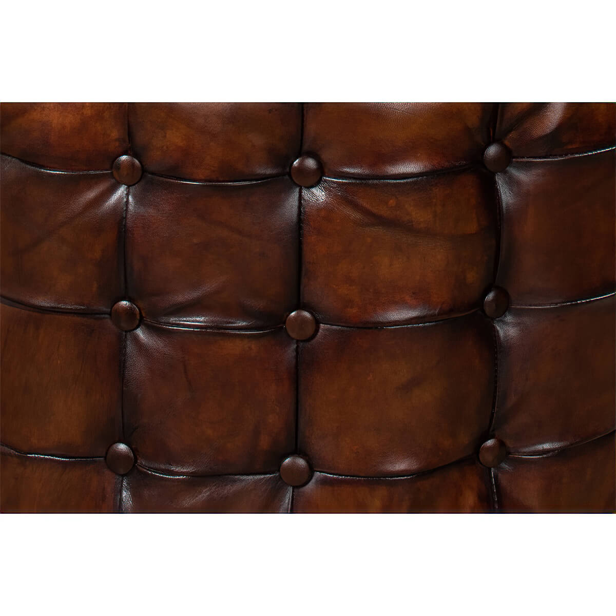 Close-up of tufted leather ottoman, brown buttons detail.