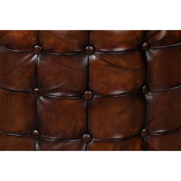 Close-up of tufted leather ottoman, brown buttons detail.