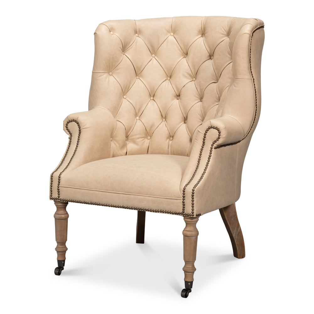 Wing chair in cappuccino brown tufted leather with brass nailhead trim and castors on the front legs