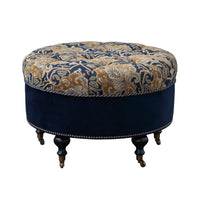 Tufted round ottoman on wooden legs, ornate design.