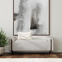Sand upholstered bench with ash end supports beneath abstract artwork, styled with a patterned pillow