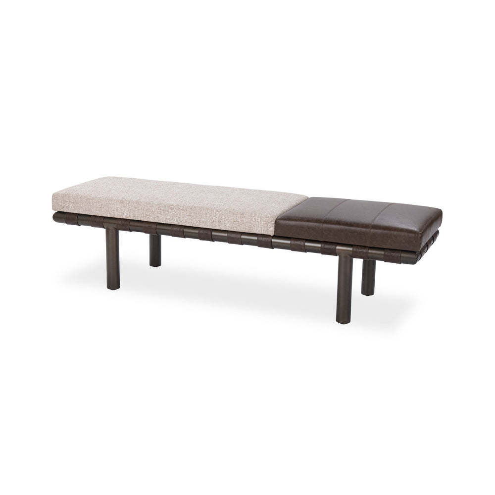 Angled view of the bench with a pale fabric seat, brown leather end cushion and leather straps over an iron frame
