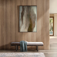 Two-tone fabric and leather bench beneath abstract artwork on a slatted wood wall, styled with a throw