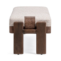 End view of the upholstered bench showing two broad wood legs and a brown band over the pale cushion