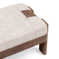 Close-up of the bench seat corner showing pale woven upholstery, a brown end band and textured brown apron