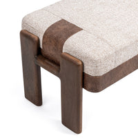 Angled end detail of the upholstered bench showing rounded wood legs and a brown band over the cushion