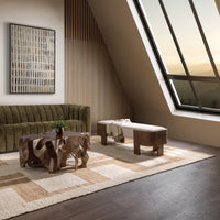 Pale upholstered bench with brown wrapped ends beside a green sofa in a room with sloped windows