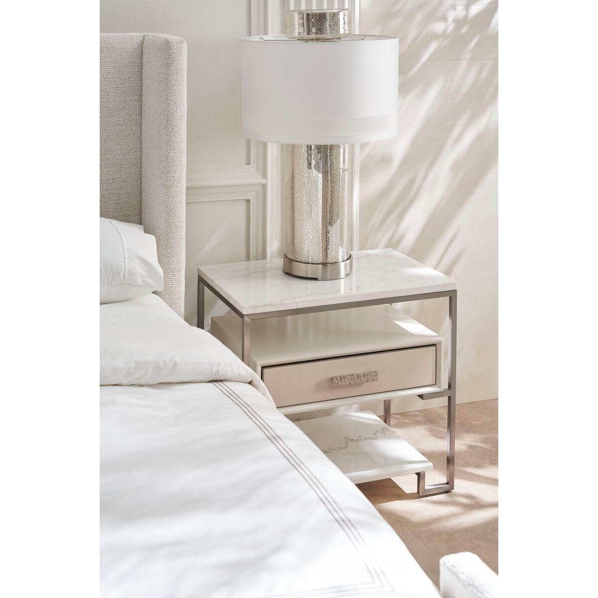 Nightstand with lamp beside the minimalist queen bed.