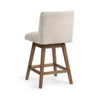Three-quarter rear view of the cream fabric swivel counter stool showing the upholstered back and angled wood legs