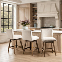 Three cream fabric swivel counter stools with brown wood legs arranged at a kitchen island