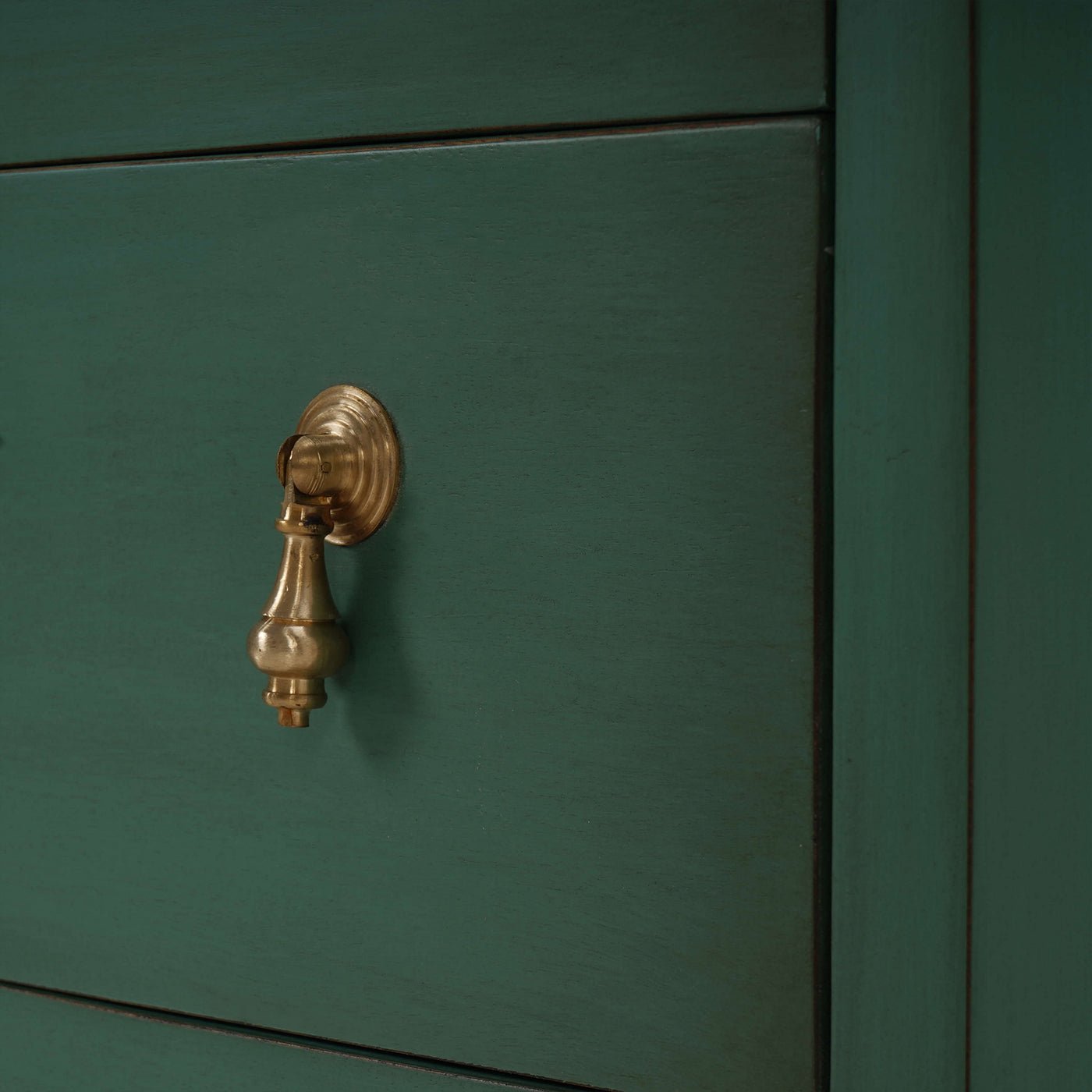Close-up of drawer handle on vintage green bedside chest.