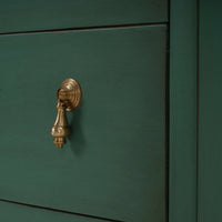 Close-up of drawer handle on vintage green bedside chest.