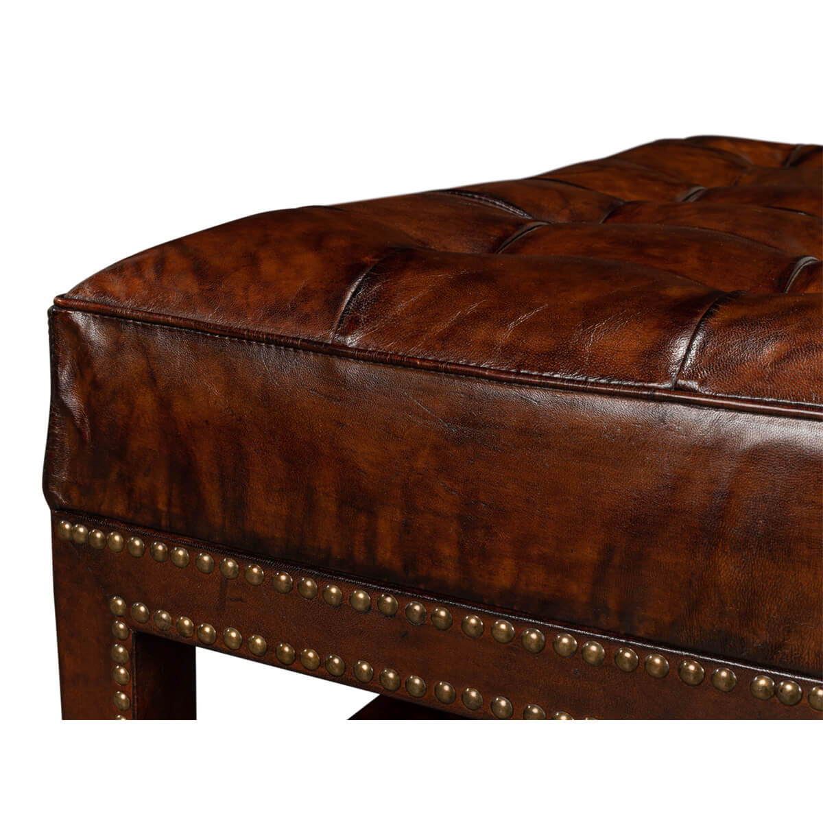 Corner focus on leather and nailhead trim of ottoman.