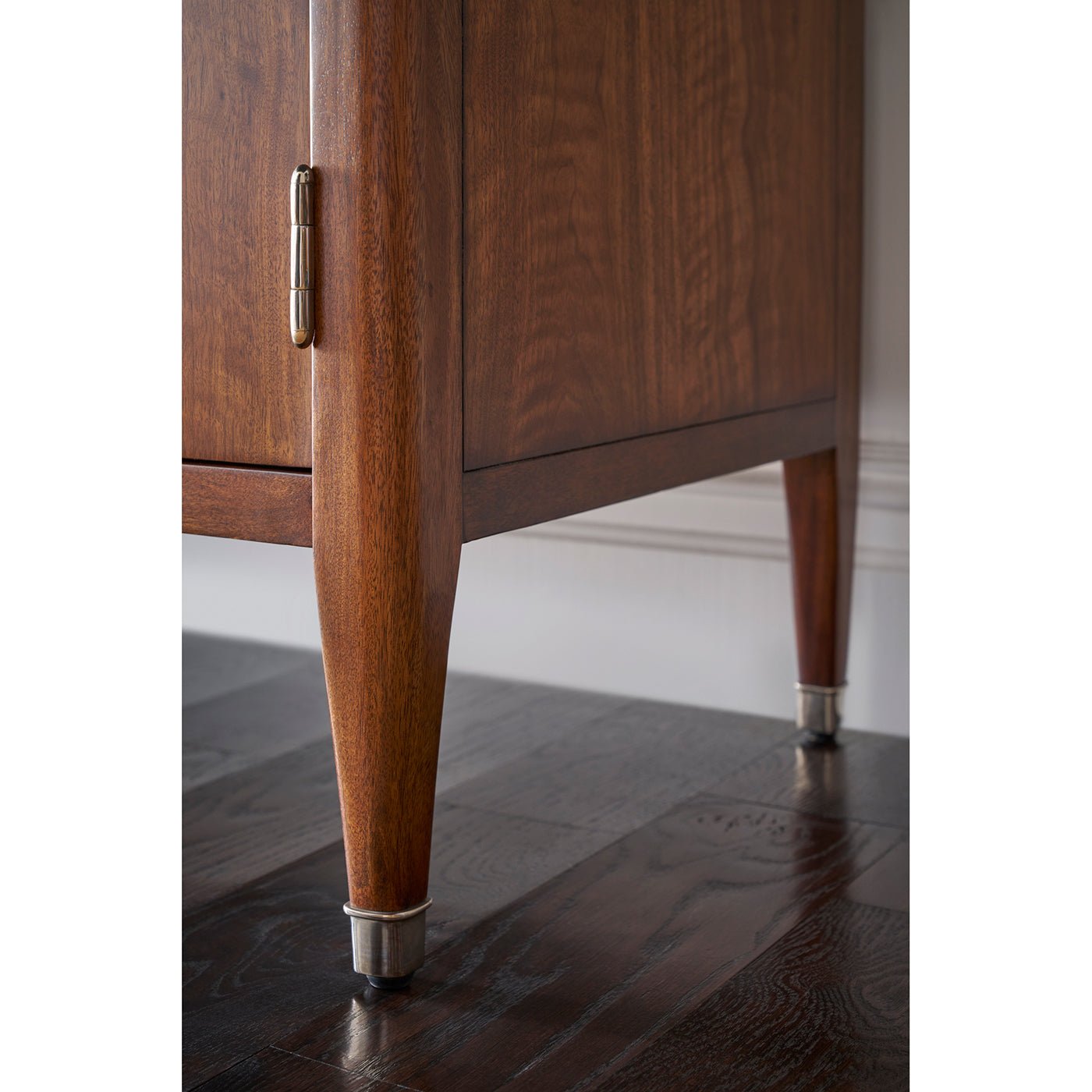 Close-up of walnut Art Deco cabinet leg with metal tip.