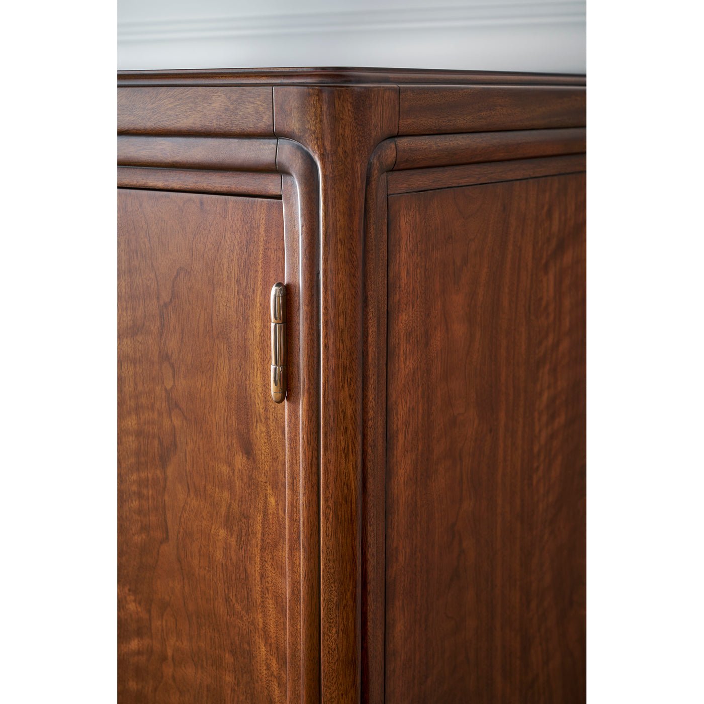 Corner detail of walnut Art Deco cabinet with visible hinge.