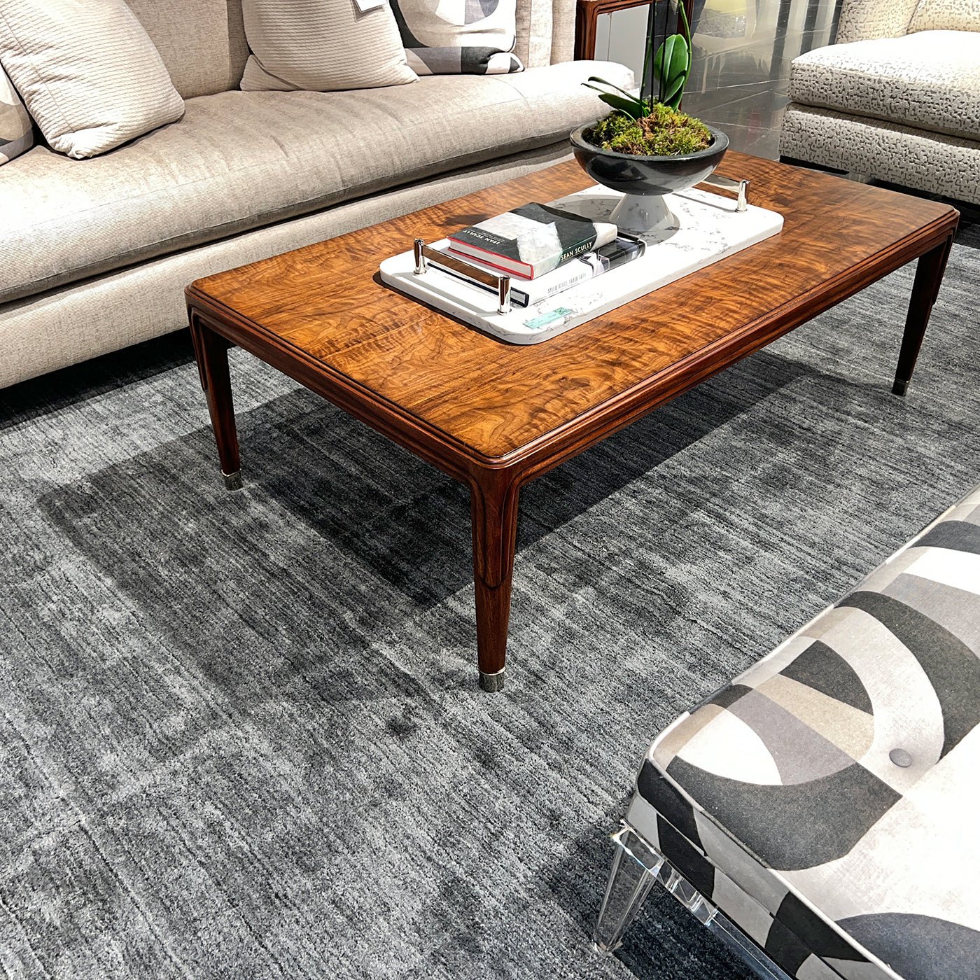 Walnut Art Deco coffee table styled with decor on gray rug.