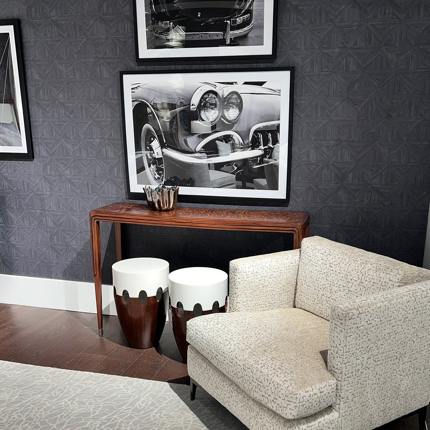 Console table beneath black-and-white photography and chair.